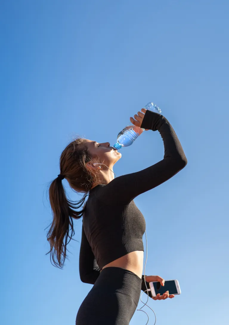 Athlete drinking water outdoors after training